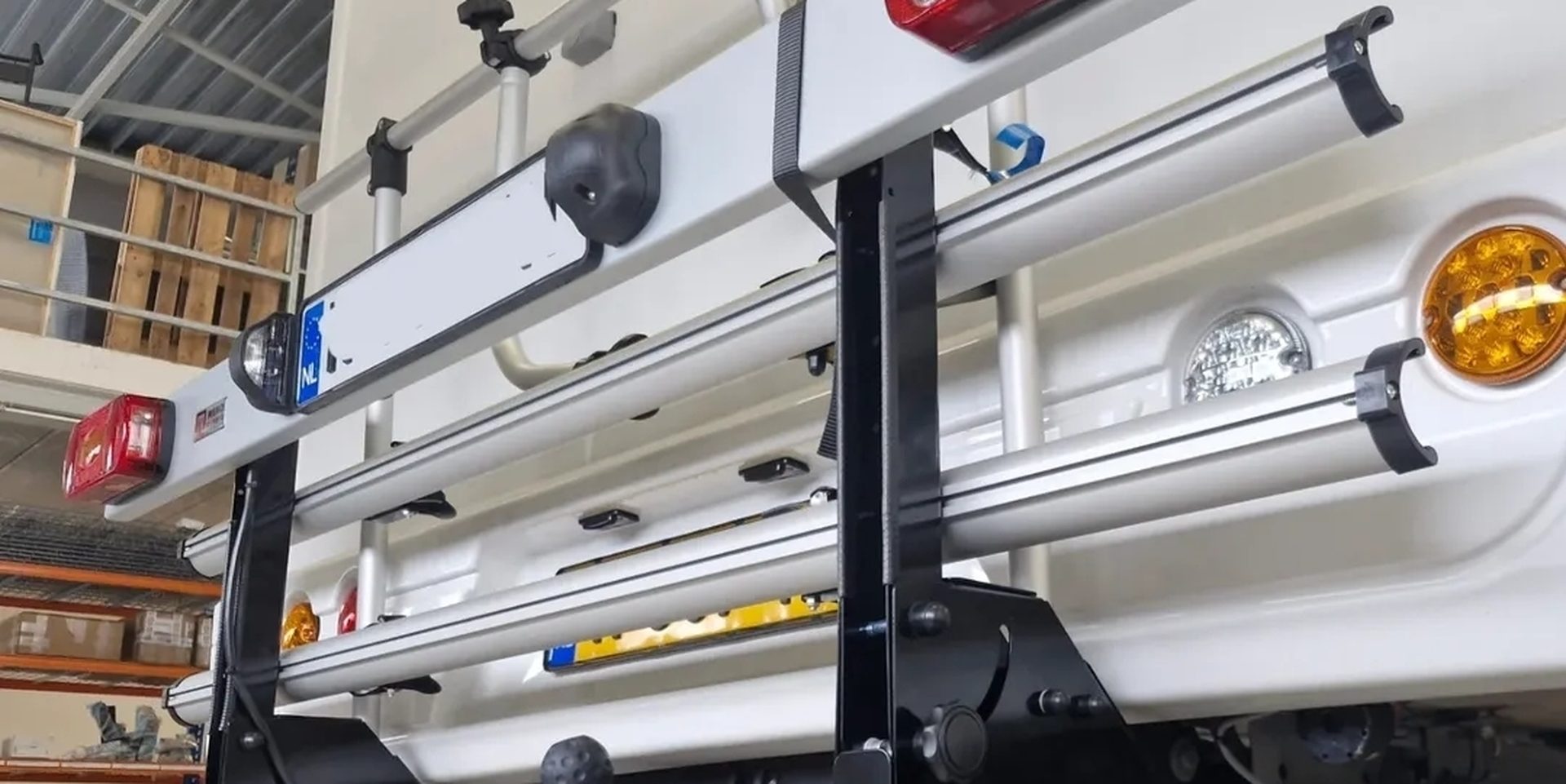Fietsendrager met verlichting en kentekenplaat, gemonteerd achter op een camper boven de trekhaak